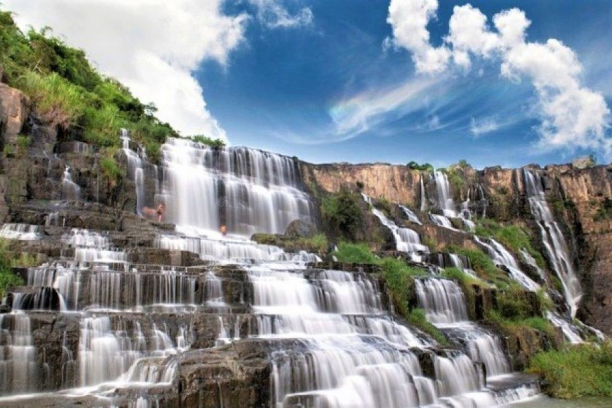 Multi-tiered waterfall with cascades and tourists for scale